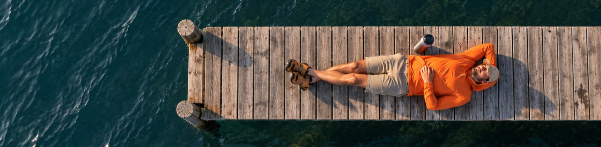 Relaxing on a lake dock in Stride Trail sun hoodie and sandals